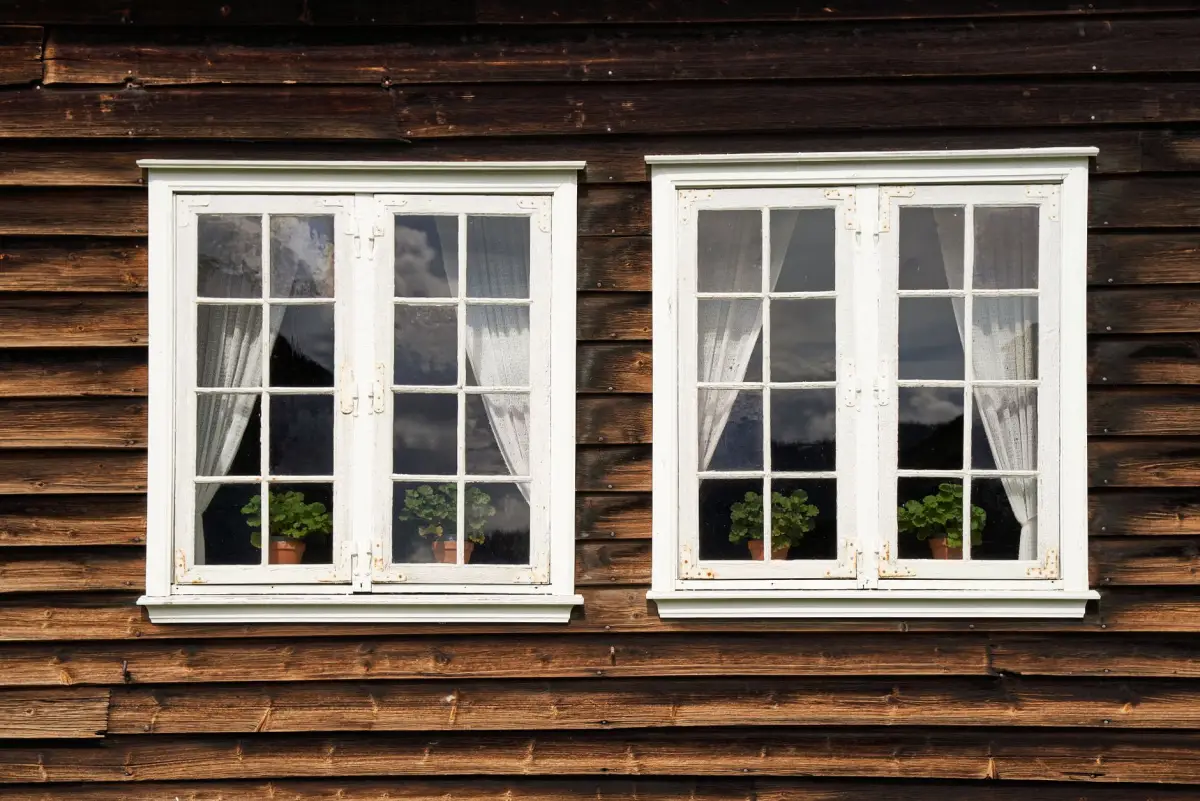 Landhuis met witte kozijnen tussen oude bomen
